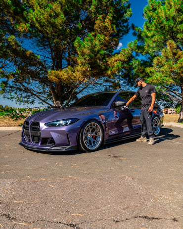 Detailer using HyperDrip products on a purple BMW parked outdoors.